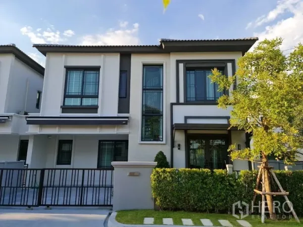 Detached House for rent in Samut Prakan - Modern two-storey detached house facade with gated driveway and landscaped hedge in Bang Phli.