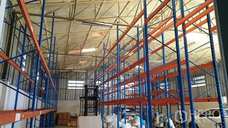 Warehouse for rent in Suan Luang, Bangkok - Central aisle lined with tall pallet racking beneath a steel insulated roof.