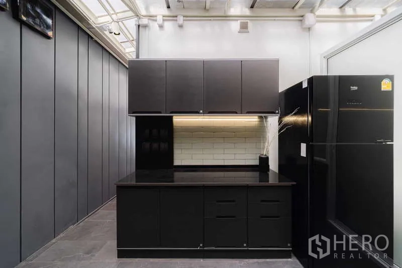 ทาวน์เฮาส์ ให้เช่าหรือขายในWatthana, Bangkok - มุมครัวตะวันตกพร้อมไอส์แลนด์ ตู้สีดำ และตู้เย็น