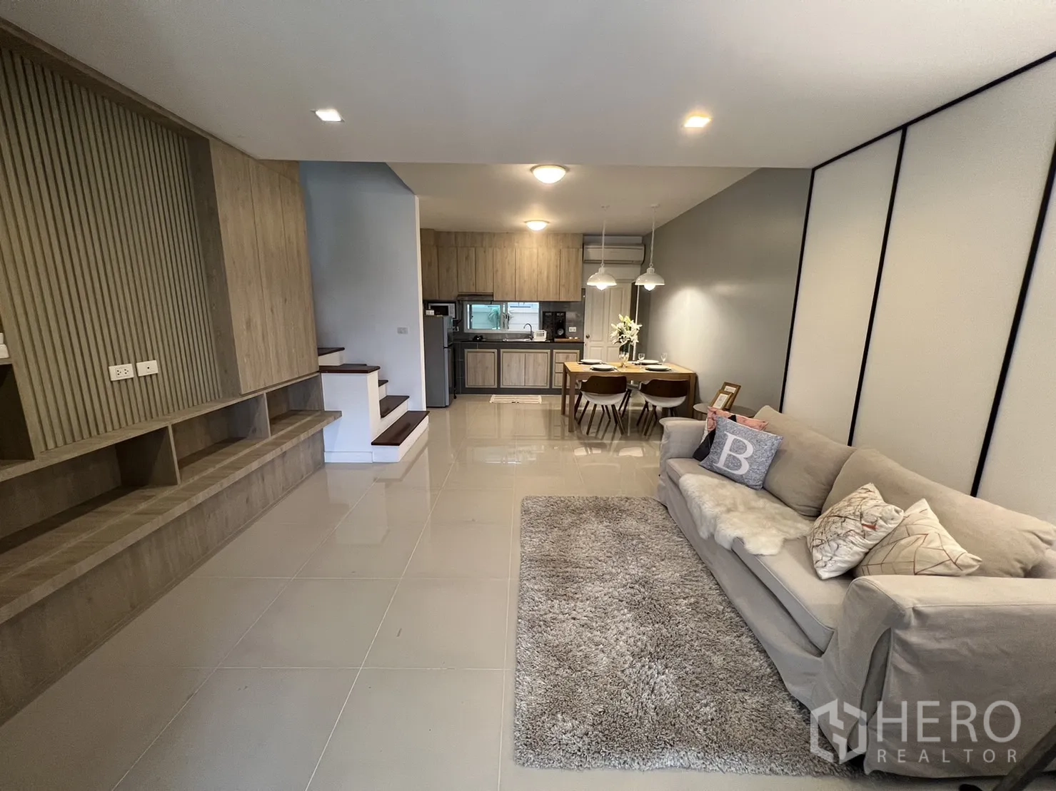 ทาวน์เฮาส์ for rent in Suan Luang, Bangkok - ห้องนั่งเล่นโอเพ่นเพลนพร้อมโซฟา พรม และมุมมองไปยังส่วนทานอาหารและครัวบิวท์อิน.
