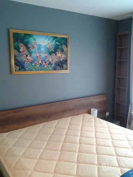 Condominium for rent in Huai Khwang, Bangkok - Bedroom with gray accent wall, wood headboard, large mattress and framed artwork, receiving natural light.