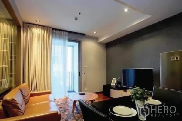 คอนโด ขายในKhlong Toei, Bangkok - ห้องนั่งเล่นอบอุ่น โซฟาหนังสีน้ำตาล ทีวี และประตูกระจกออกระเบียง