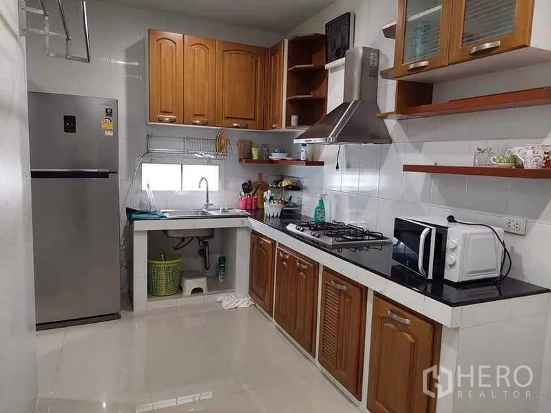 Detached House for sale in Bueng Kum, Bangkok - Fitted kitchen with wooden cabinets, gas hob, extractor hood, fridge and microwave.