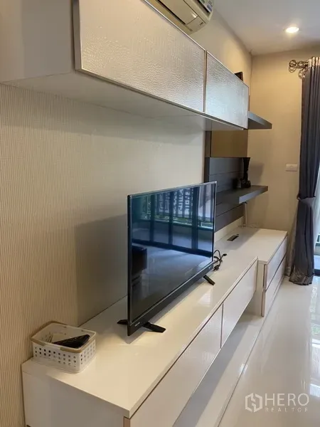 Condominium for rent in Watthana, Bangkok - Built-in media wall with flat-screen TV and ample storage cabinets in the living area.