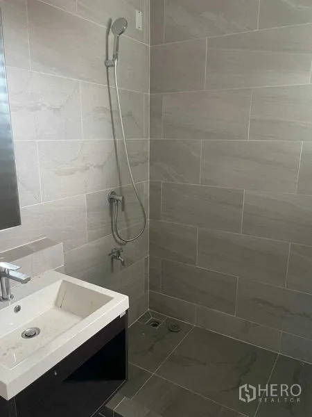 Townhouse for sale in Bueng Kum, Bangkok - Compact bathroom with gray tiles, vanity and handheld shower.