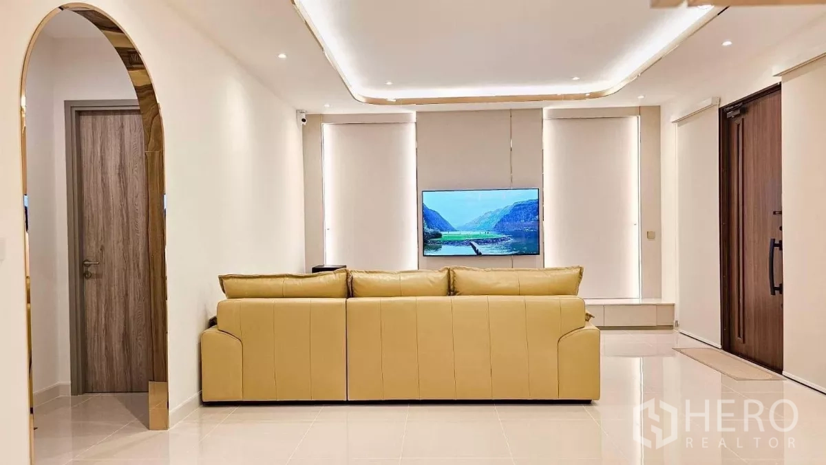 บ้าน ให้เช่าหรือขายในPrawet, Bangkok - มุมห้องรับแขกมินิมอล ซุ้มโค้ง หน้าต่างบานใหญ่ และผนังทีวีหลังโซฟาสีครีม