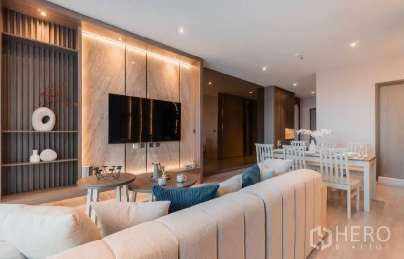 Condominium for rent in Watthana, Bangkok - Open-plan lounge and dining area with marble feature wall and recessed lighting.