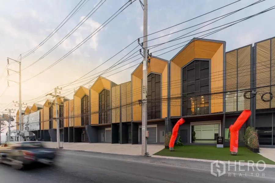 คลังสินค้า ให้เช่าในMueang Samut Sakhon, Samut Sakhon - อาคารโกดังสไตล์โมเดิร์นลอฟท์เรียงกันริมถนนใหญ่ พร้อมทางเข้าและลูกโป่งลมสีแดงในช่วงเย็น