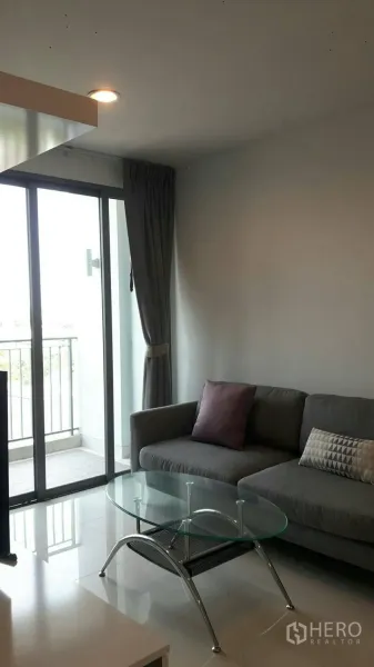 公寓 出租在Phaya Thai, Bangkok - 沙发角与玻璃茶几，落地阳台门可欣赏城市景观。