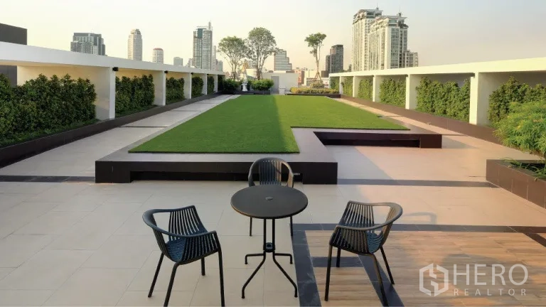 Condominium for rent or sale in Watthana, Bangkok - Rooftop garden terrace with table, chairs and Watthana city skyline views.