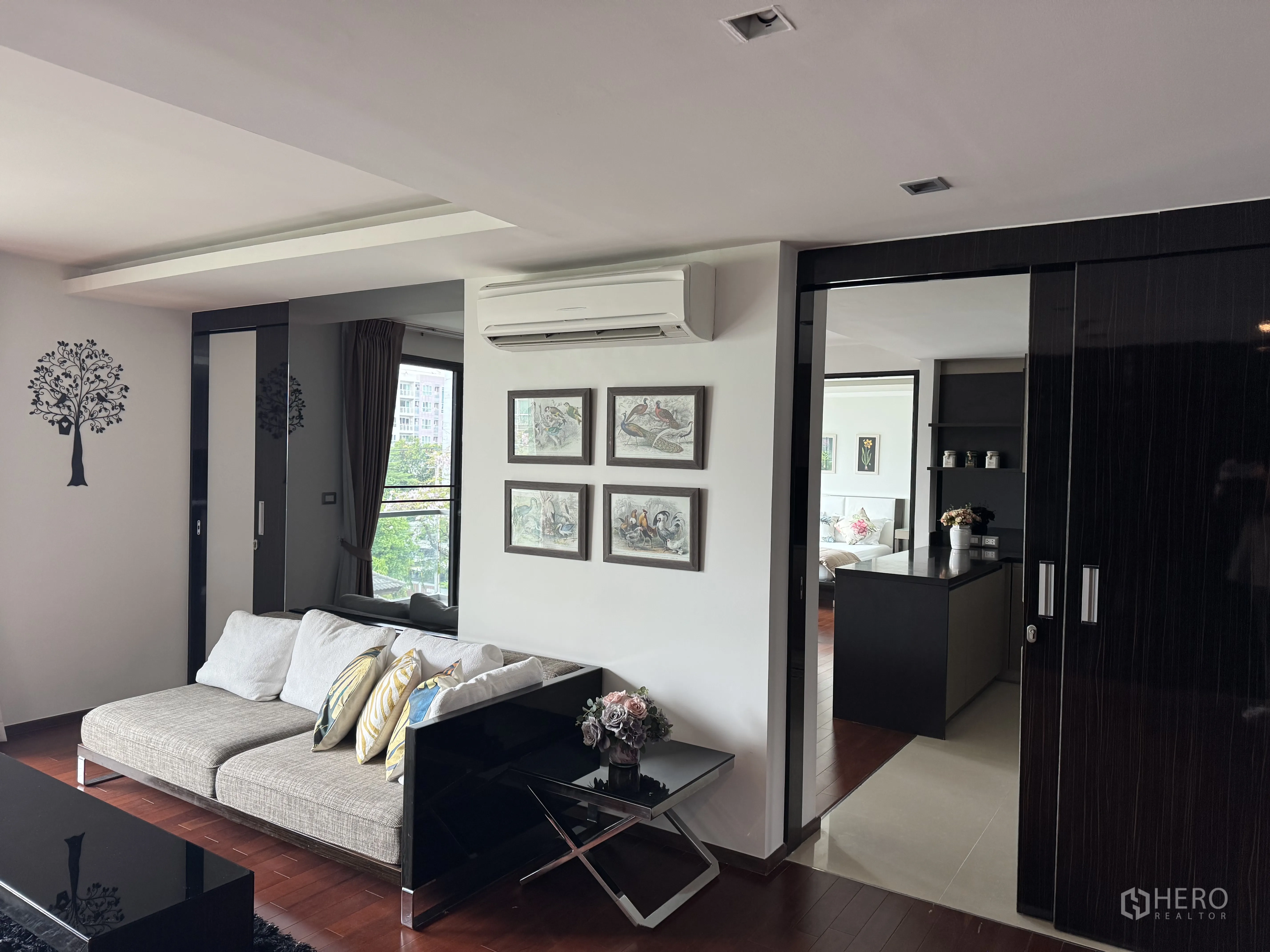 Condominium for rent in Watthana, Bangkok - Living area with sofa, TV console, sliding doors, and wood flooring.