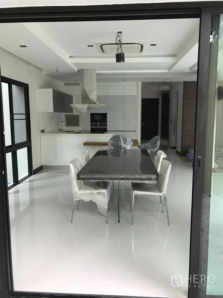 บ้าน ให้เช่าในBang Kapi, Bangkok - มุมมองผ่านประตูกระจกสู่โซนรับประทานอาหารและครัวสีขาว ฝ้าแอร์แขวนเพดาน