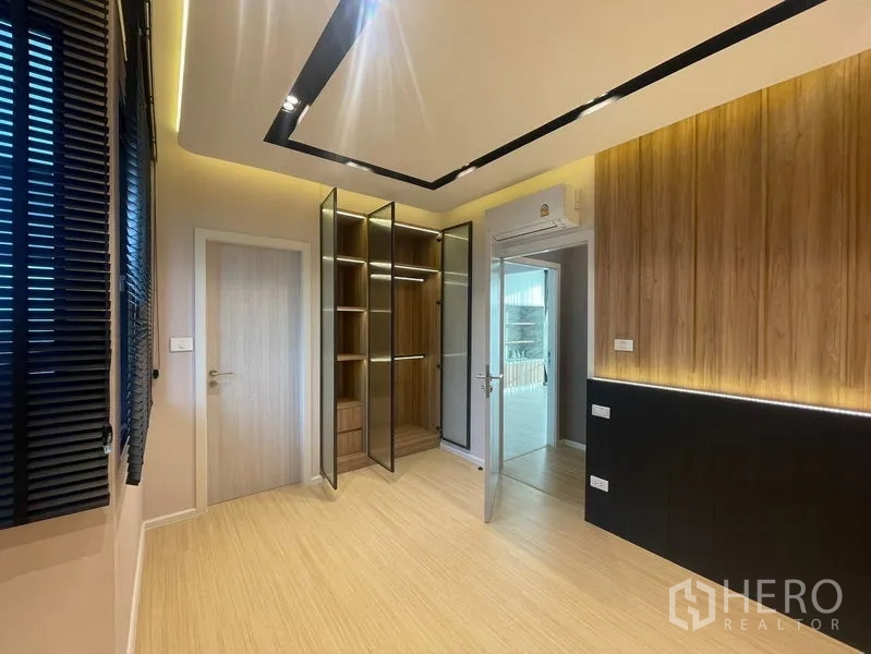 Townhouse for sale - Bedroom with illuminated wood feature wall and glass‑door wardrobe cabinetry.