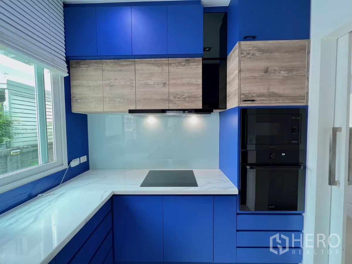 独立式住宅 出租或出售在Khlong Luang, Pathum Thani - 现代U形厨房，蓝色柜体、感应炉与白色台面