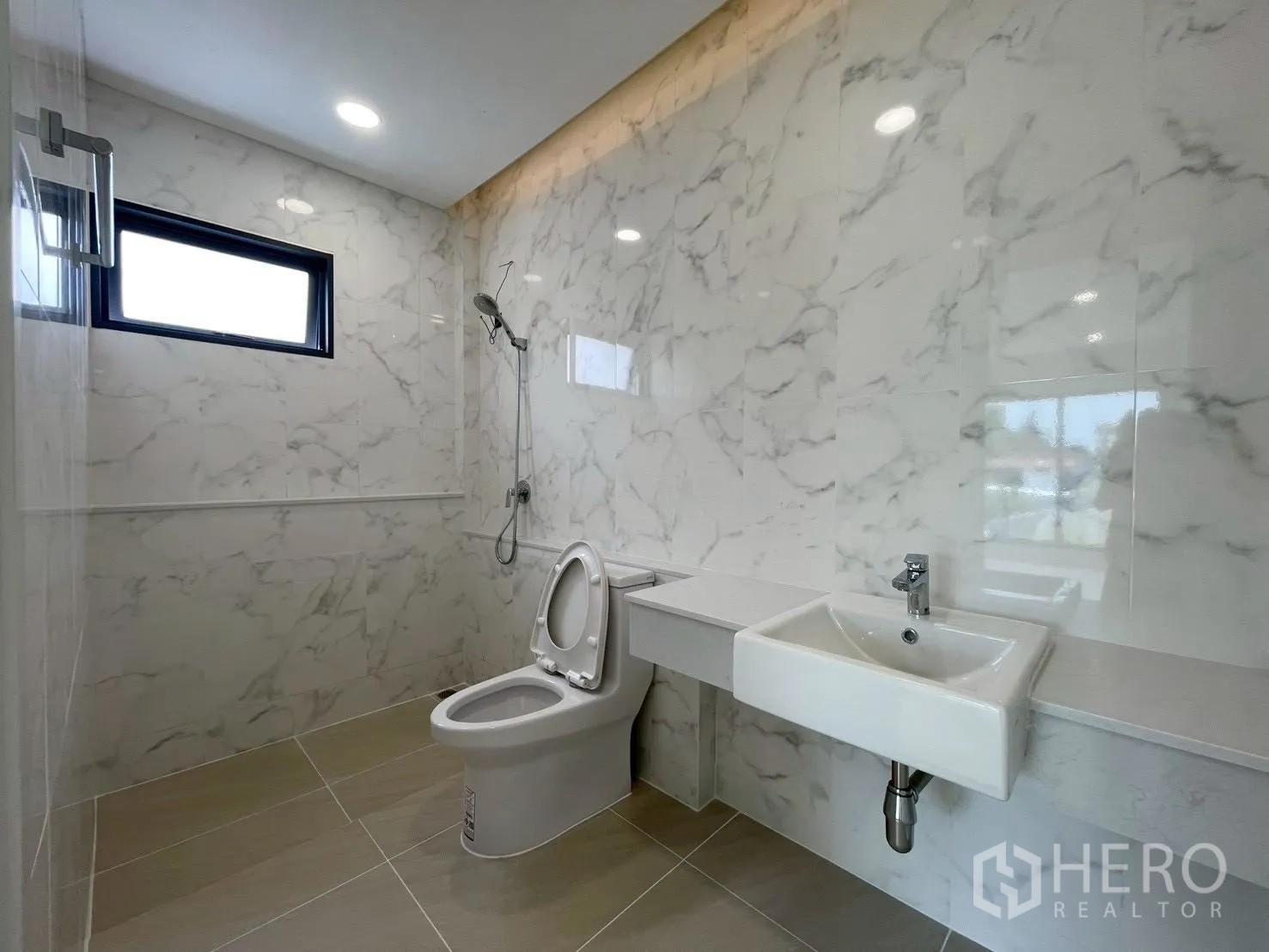 Detached House for sale in Chatuchak, Bangkok - Secondary bathroom with marble-effect tiles, shower, toilet, and compact basin.