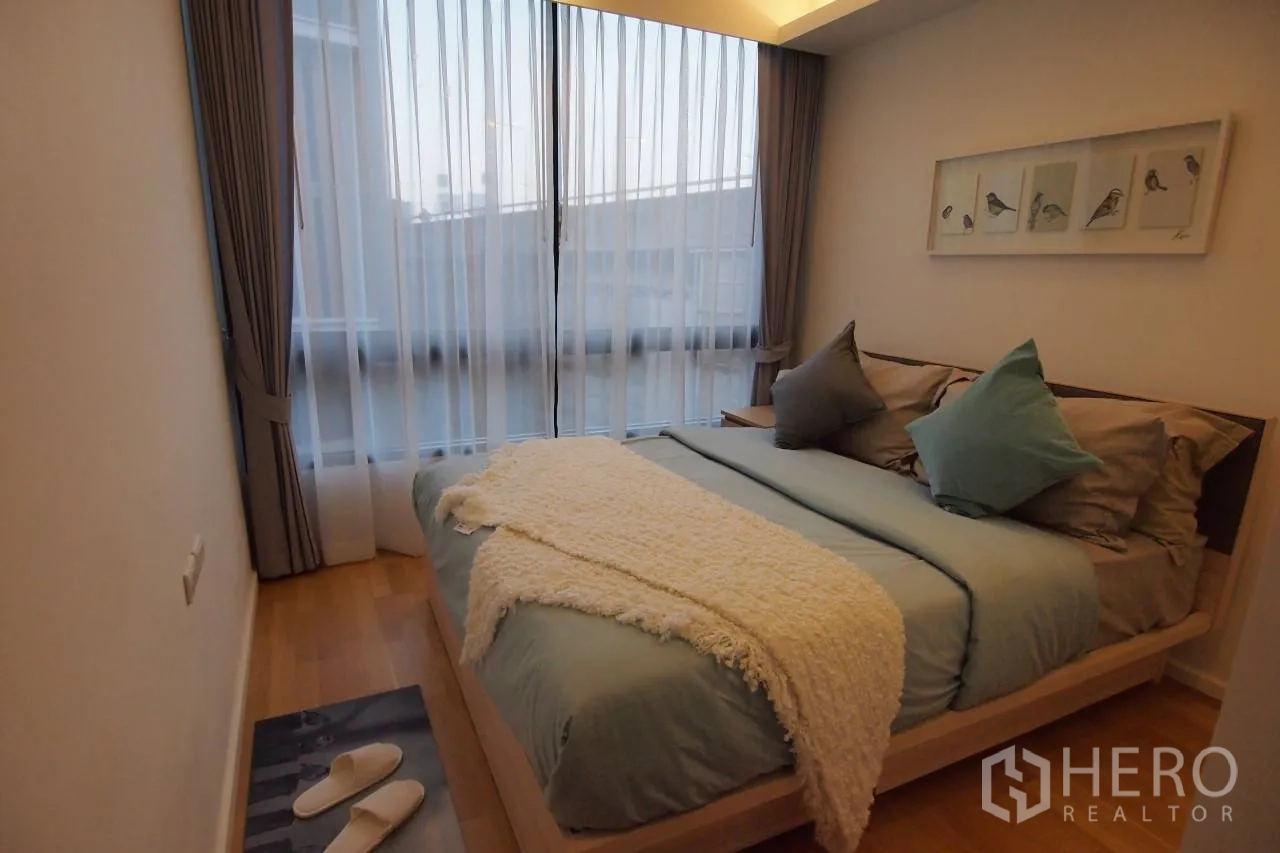 Condominium for rent in Pathum Wan, Bangkok - Bright bedroom with large window, curtains and a double bed with soft pillows.