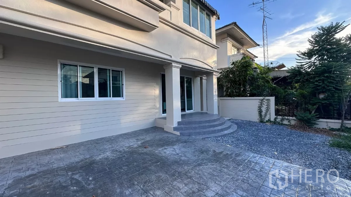 บ้าน ให้เช่าในLat Krabang, Bangkok - เฉลียงหน้าบ้านพร้อมบันไดโค้ง เสาและประตูกระจกบานเลื่อน มีสวนข้างบ้านเล็ก ๆ