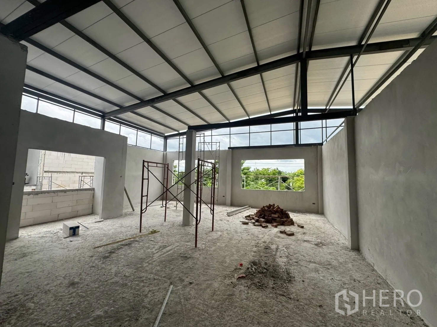 Factory for rent in Phutthamonthon, Nakhon Pathom - Large unfinished office space with high ceiling, big window openings, and scaffolding.