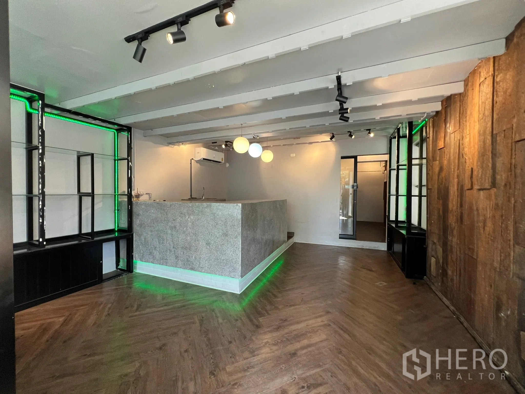 零售空间 出租在Watthana, Bangkok - 开放式销售区，鱼骨拼木地板、木质特色墙与绿色LED展示架