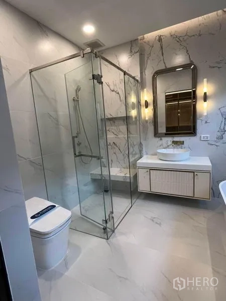 Detached House for rent in Saphan Sung, Bangkok - Bathroom featuring glass-enclosed shower, wall-mounted vanity and marble tiles.