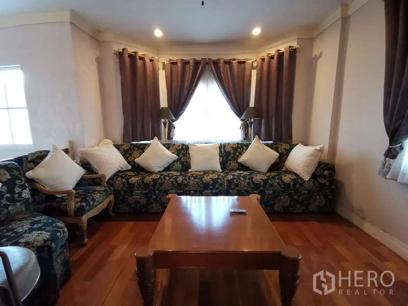 独立式住宅 出售在Phra Khanong, Bangkok - 起居室设花纹沙发、木地板与中央茶几。