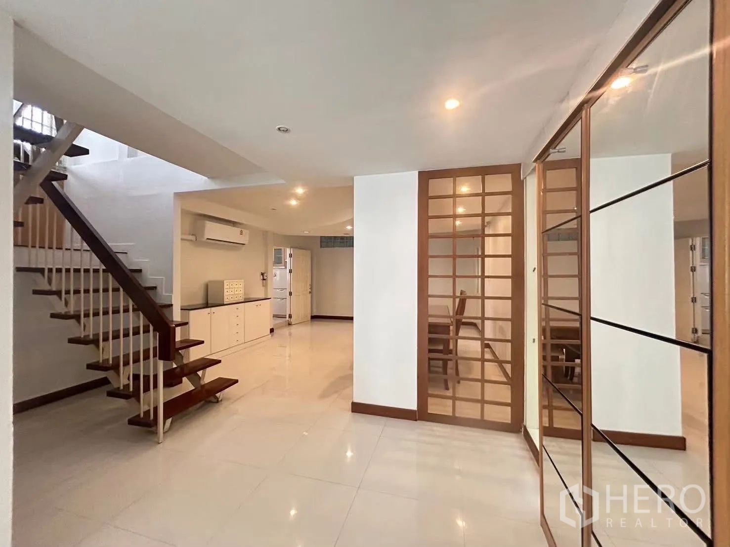 Detached House for rent in Suan Luang, Bangkok - Entry hall featuring an open wooden staircase, glossy floor tiles, and glass partition doors.