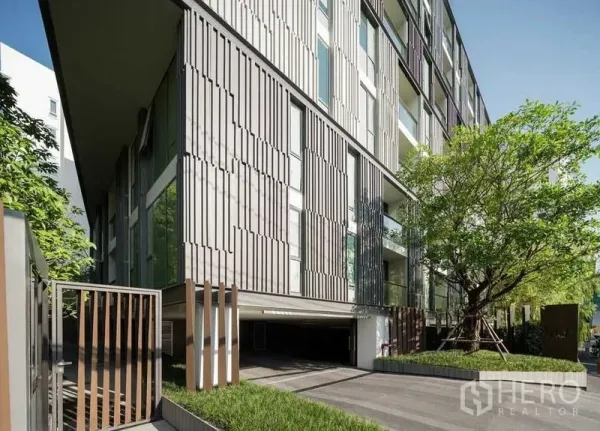 คอนโด ให้เช่าหรือขายในWatthana, Bangkok - อาคารคอนโดโลว์ไรส์สมัยใหม่ มีกระจกและระแนงแนวตั้ง พร้อมทางเข้าและต้นไม้ใหญ่