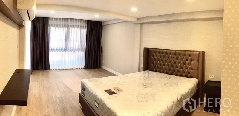 联排别墅 出租在Khlong Toei, Bangkok - 宽敞卧室，纽扣软包床头、木地板与大窗。