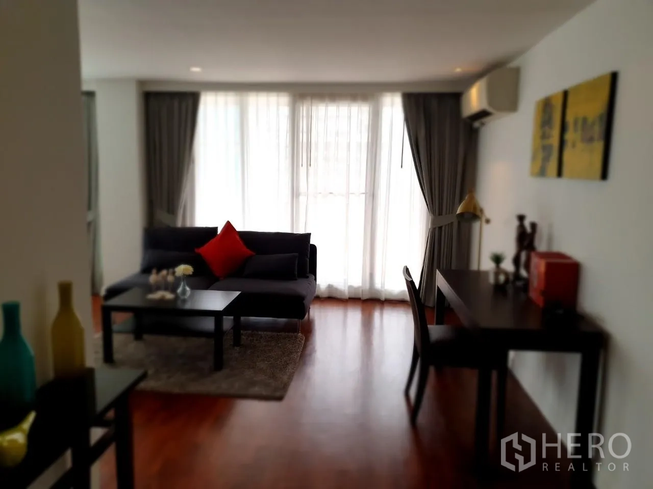 Apartment for rent in Bang Rak, Bangkok - Cozy sitting area with sofa, coffee table, work desk and full-height curtains.