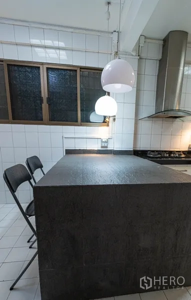 Townhouse for rent in Khlong Toei, Bangkok - Close‑up of kitchen island with two stools and hanging pendant lights.