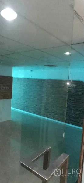 Office Space for rent in Huai Khwang, Bangkok - Reception area with glass entry and a textured feature wall under spotlights.