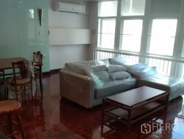 อพาร์ทเมนท์ ให้เช่าในPathum Wan, Bangkok - ห้องนั่งเล่นสว่างของอพาร์ตเมนต์ย่านลุมพินี มีหน้าต่างบานใหญ่ พื้นปาร์เกต์ โซฟาสีเทา และโต๊ะกลาง ใกล้ BTS เพลินจิต