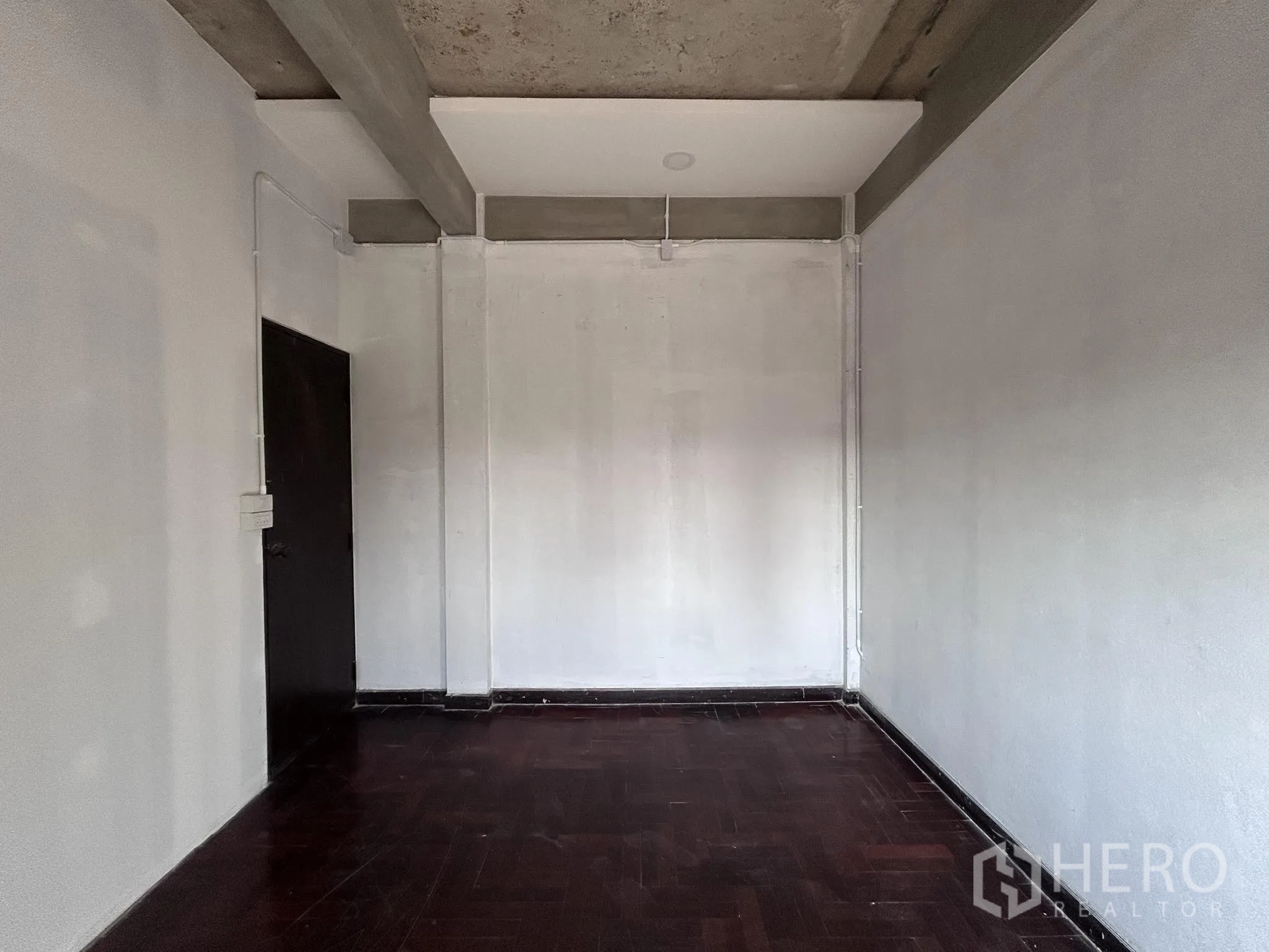 家庭办公室 for rent or sale in Watthana, Bangkok - 空房，深色木地板与简洁墙面、天花梁。