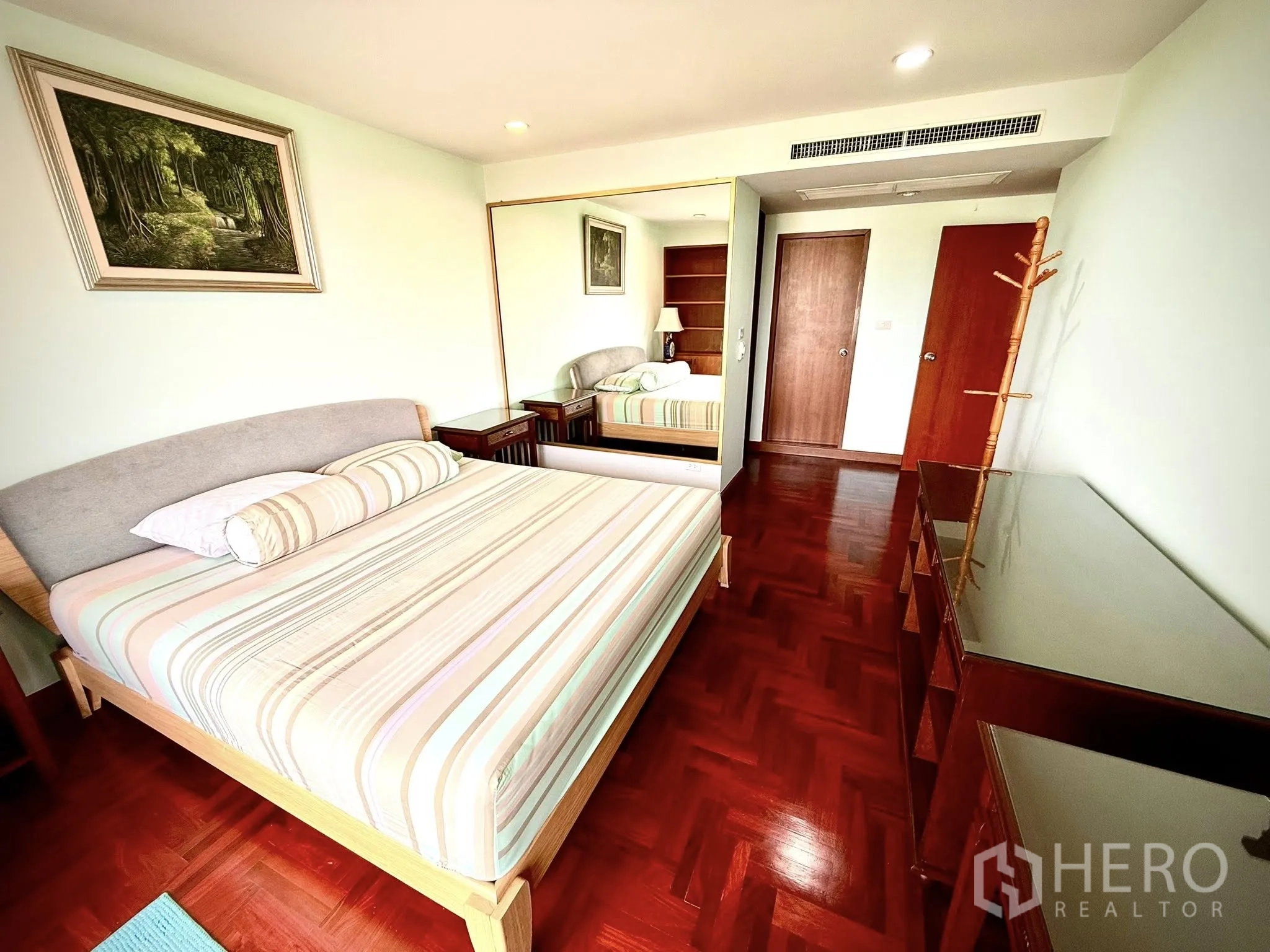 Condominium for rent in Sathon, Bangkok - Master bedroom with striped bedding, bedside tables and mirrored wardrobe.