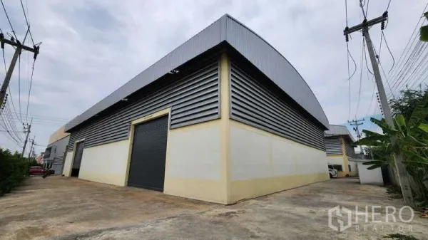 工厂 出租在Ban Phaeo, Samut Sakhon - 工厂外观为金属板包覆，配大型卷闸门与宽阔车道，方便集装箱车进出。