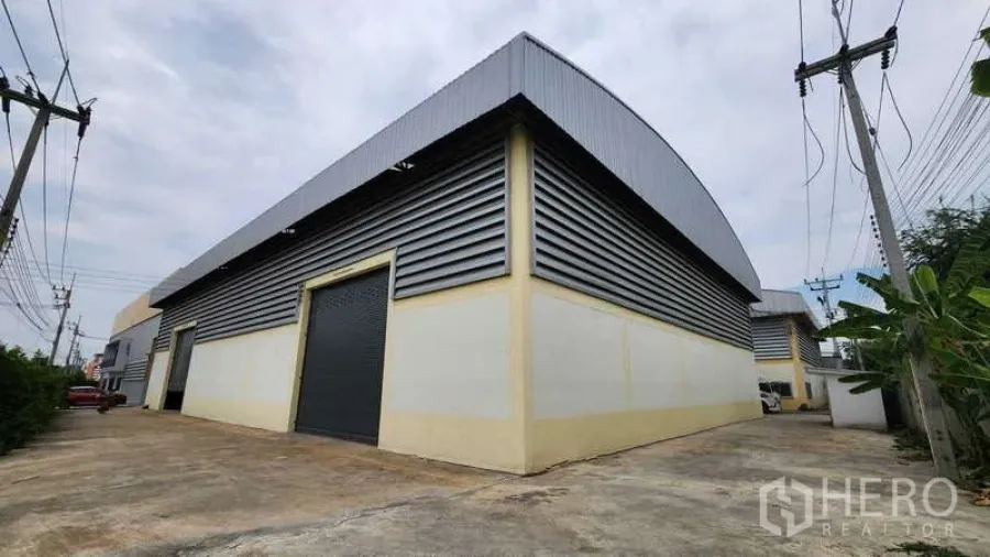 工厂 出租在Ban Phaeo, Samut Sakhon - 工厂外观为金属板包覆，配大型卷闸门与宽阔车道，方便集装箱车进出。