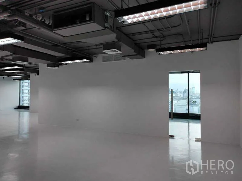สำนักงาน ให้เช่า - โซนออฟฟิศกว้าง ไฟแขวนเพดาน และประตูกระจกเปิดสู่มุมมองเมือง.