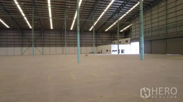 Warehouse for rent in Bang Phli, Samut Prakan - Expansive warehouse floor with roof lighting, roll-up doors and a small office block.