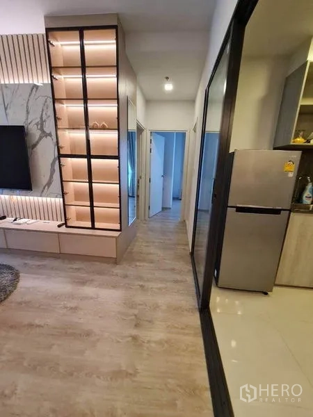 คอนโด ให้เช่า - โถงทางเดินจากห้องนั่งเล่นสู่ห้องนอน พร้อมตู้โชว์ไฟในตัวและมองเห็นโซนครัว