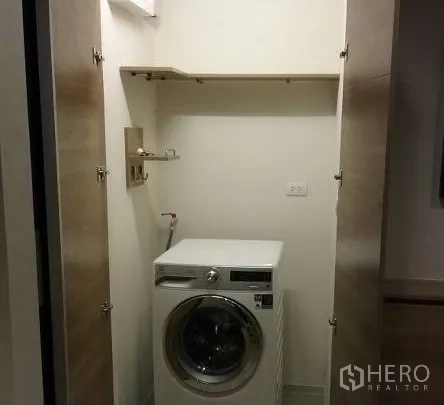 Condominium for rent in Sathon, Bangkok - Laundry closet with front-loading washing machine and overhead shelving.
