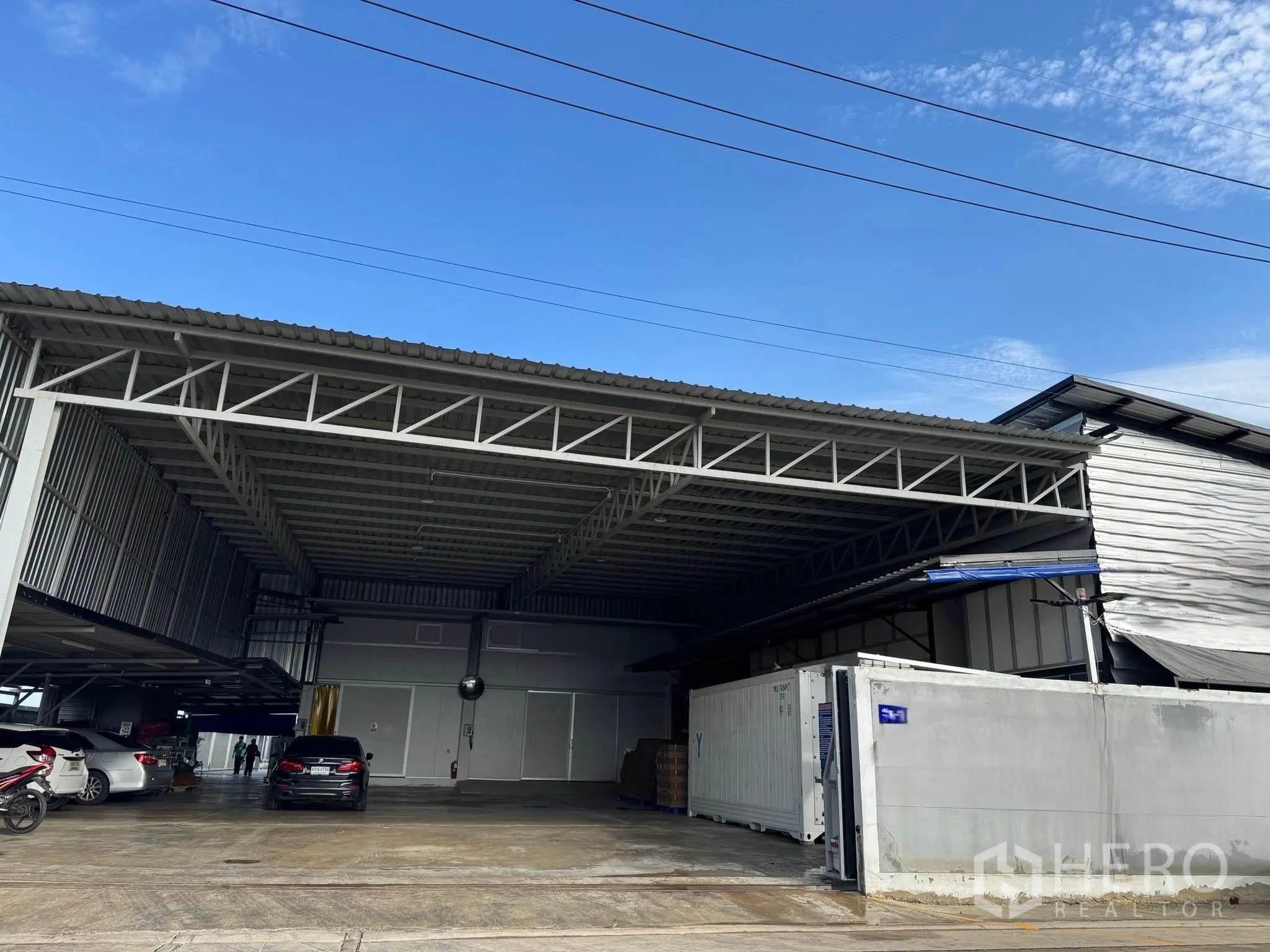 工厂 for rent in Mueang Samut Sakhon, Samut Sakhon - 钢结构工厂外观，宽阔遮棚装卸区、停车位与集装箱。