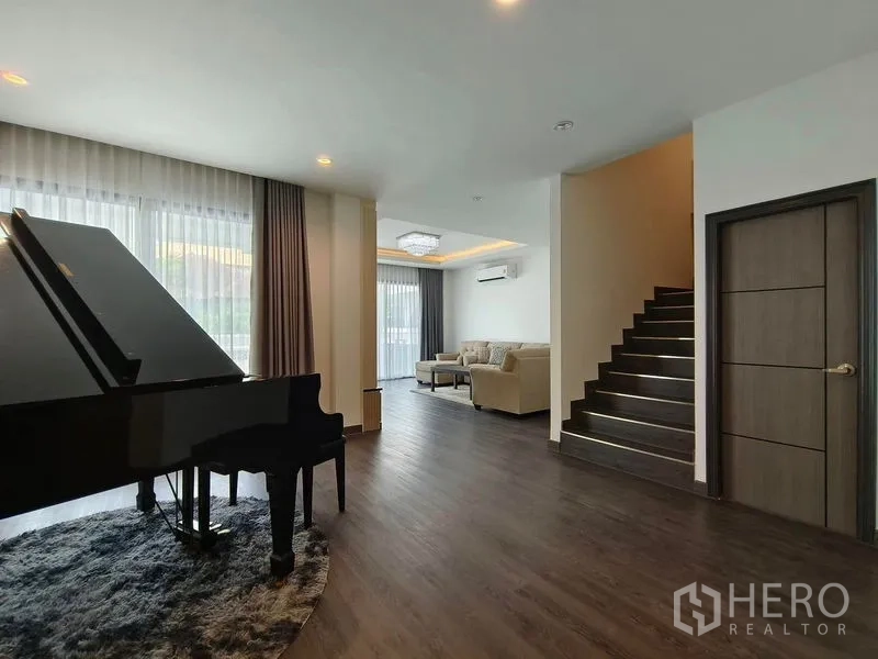Detached House for rent or sale - Bright living room with grand piano, staircase, and floor-to-ceiling windows in a modern Sukhumvit detached house.
