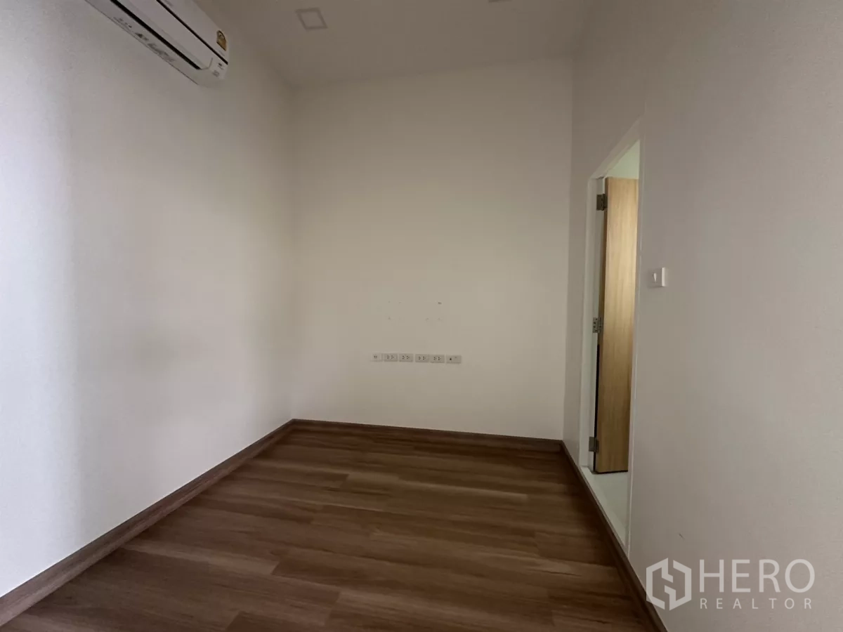 零售空间 出租在Phra Khanong, Bangkok - 简洁房间，木地板、分体空调与通往附属空间的门。