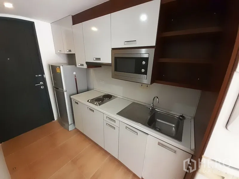 คอนโด ให้เช่าในPathum Wan, Bangkok - ครัวบิลต์อินสไตล์โมเดิร์น มีตู้ลอย ไมโครเวฟ เตาไฟฟ้า อ่างล้างจาน และตู้เย็น