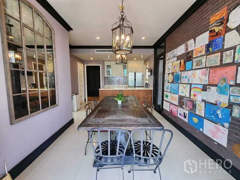 Condominium for sale in Khlong Toei, Bangkok - Dining area with rustic long table, pendant chandeliers and art display wall.