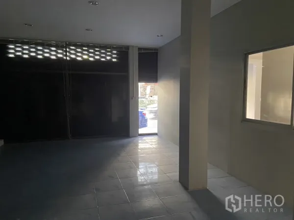 店屋 出租在Bang Na, Bangkok - 前厅铺面，瓷砖地面，卷闸门半开引入自然采光