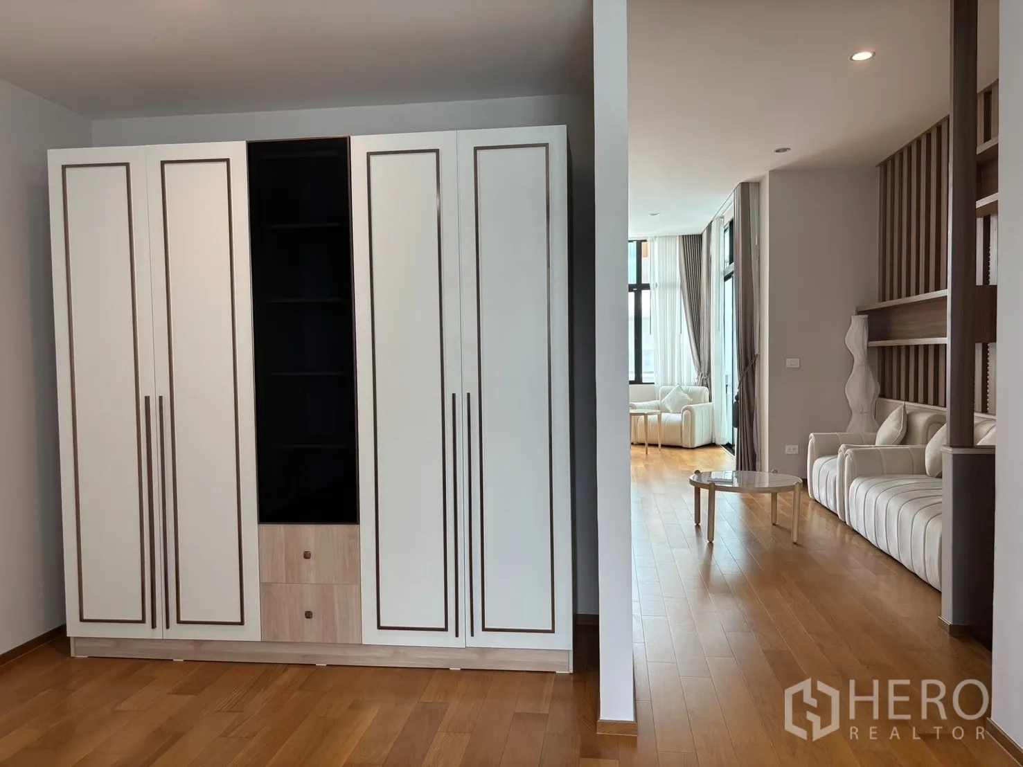Townhouse for rent in Saphan Sung, Bangkok - Sitting area with a tall wardrobe and a glimpse of the living zone with sofa.