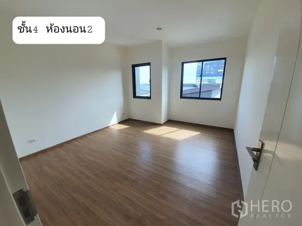 Home Office for rent or sale in Prawet, Bangkok - Bright upper-floor bedroom with wood flooring and two windows allowing natural light.
