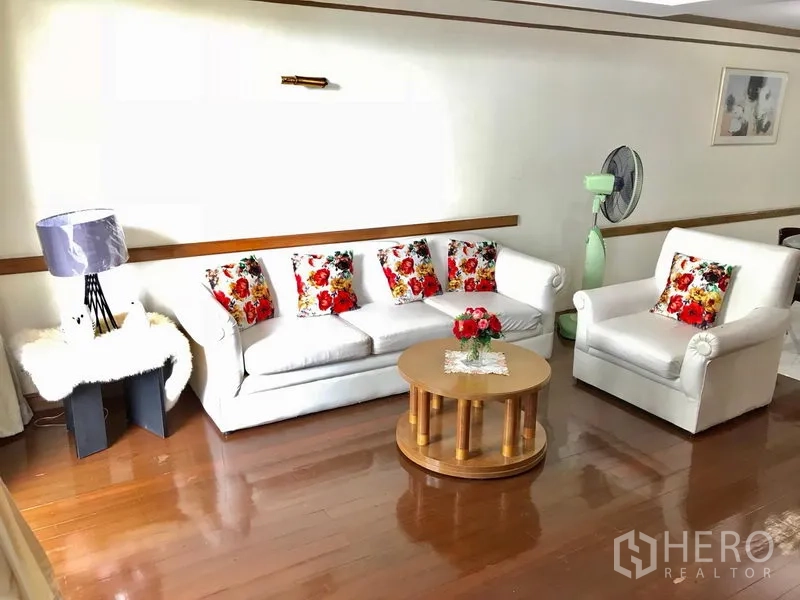 คอนโด ให้เช่าในWatthana, Bangkok - มุมนั่งเล่นสว่างด้วยโซฟาสีขาว หมอนลายดอก โต๊ะกาแฟทรงกลม บนพื้นไม้