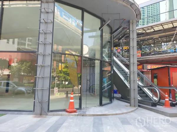 零售空间 出租在Watthana, Bangkok - 转角铺面，弧形落地玻璃，旁有室外自动扶梯的商业空间。